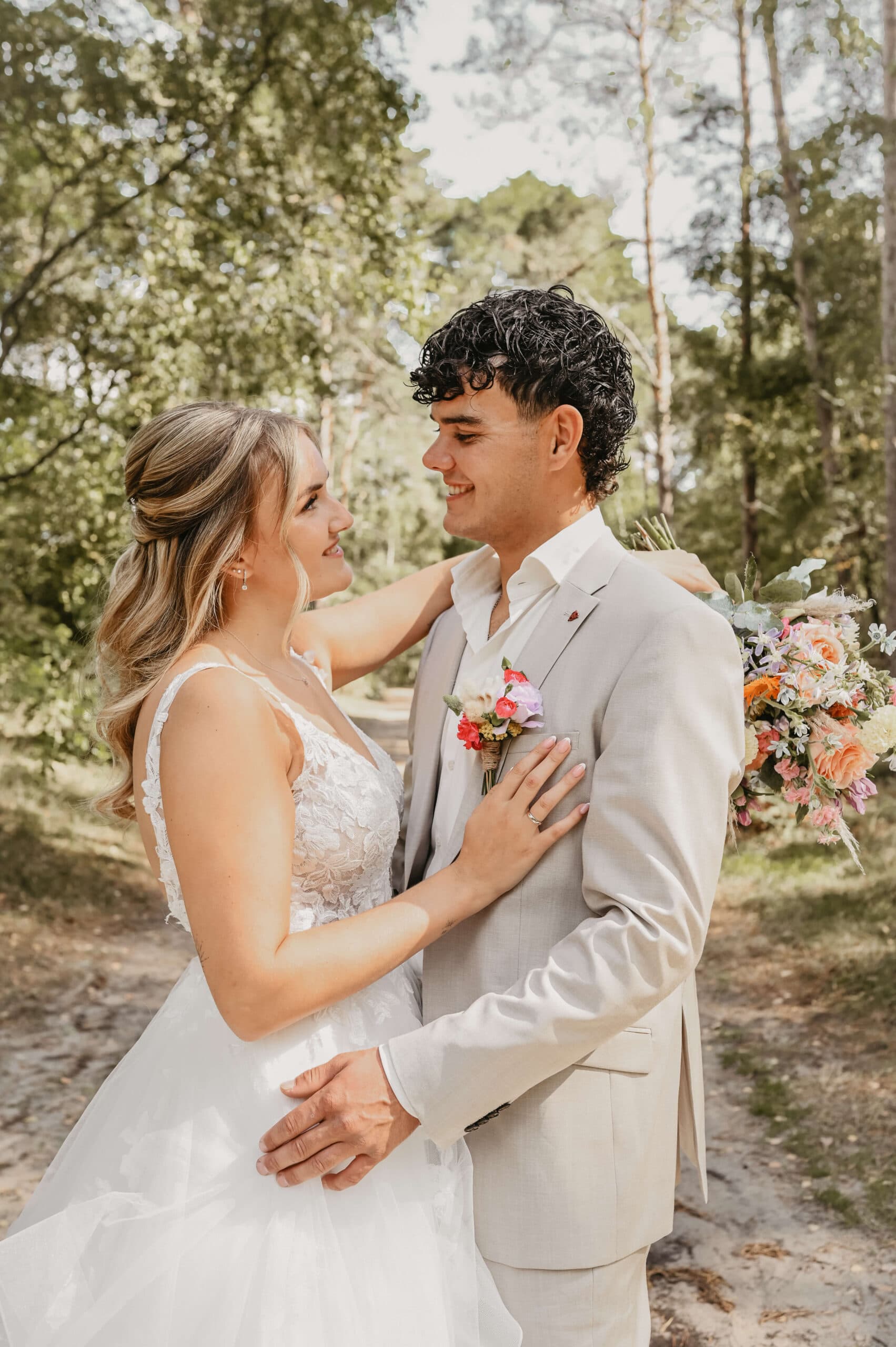 Bruidspaar kijkt elkaar lachend aan in het bos – Studio Roos Fotografie