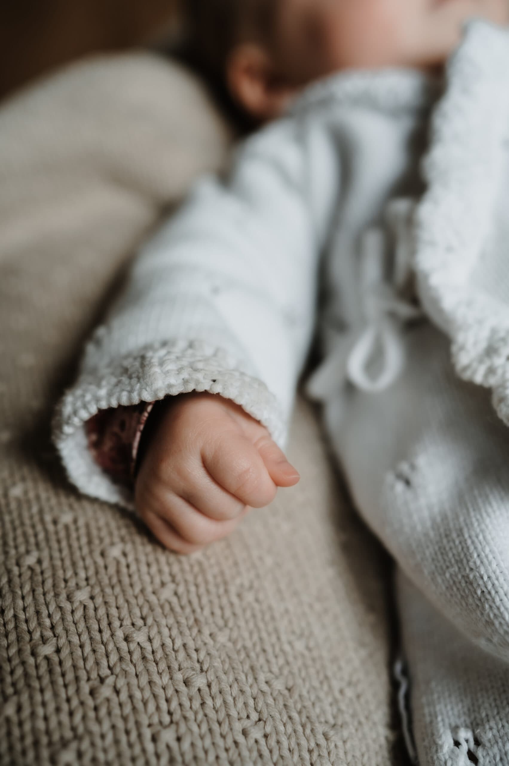Close-up van klein babyhandje in wit vestje – Studio Roos Fotografie