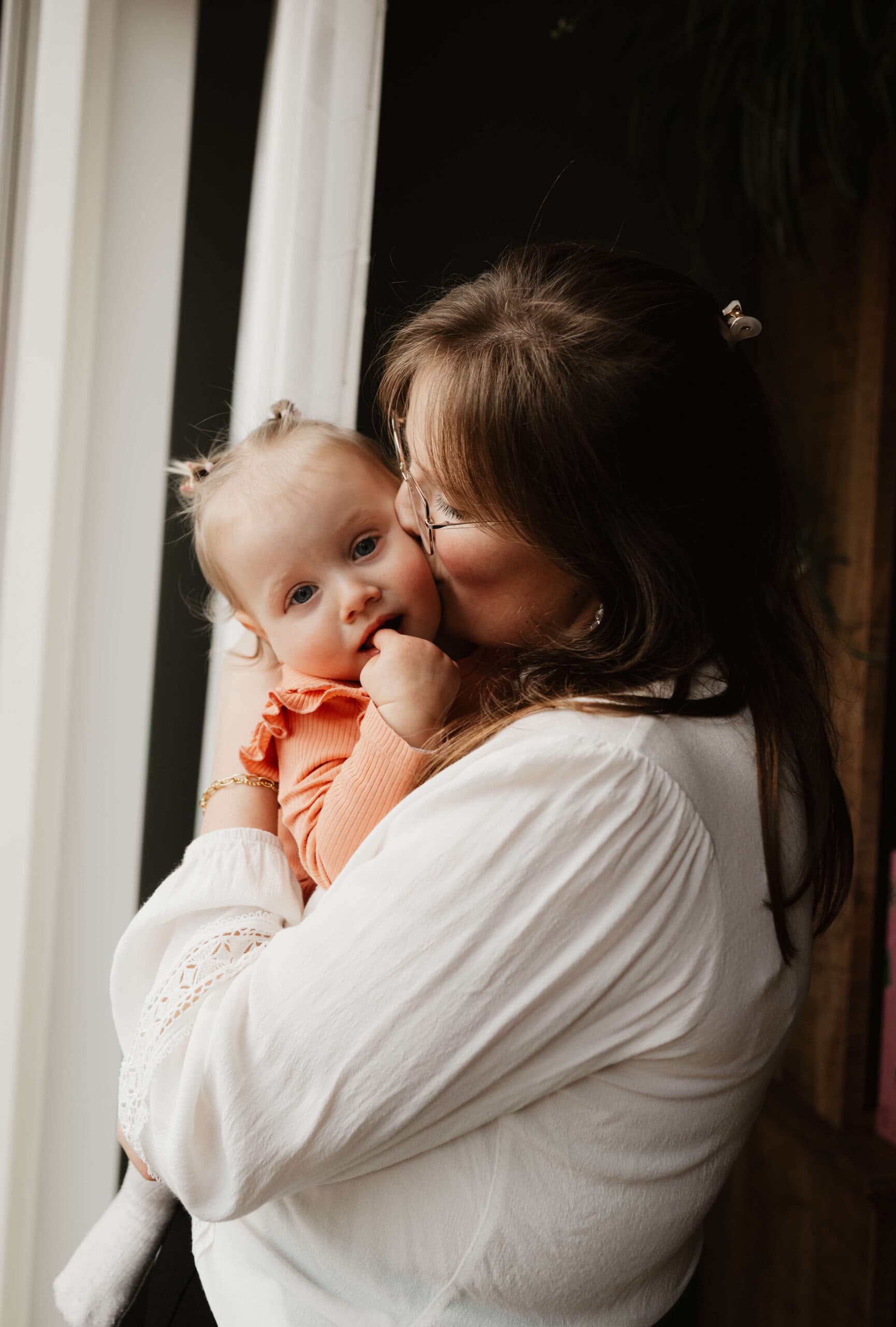 Moeder kust haar baby bij het raam – Studio Roos Fotografie
