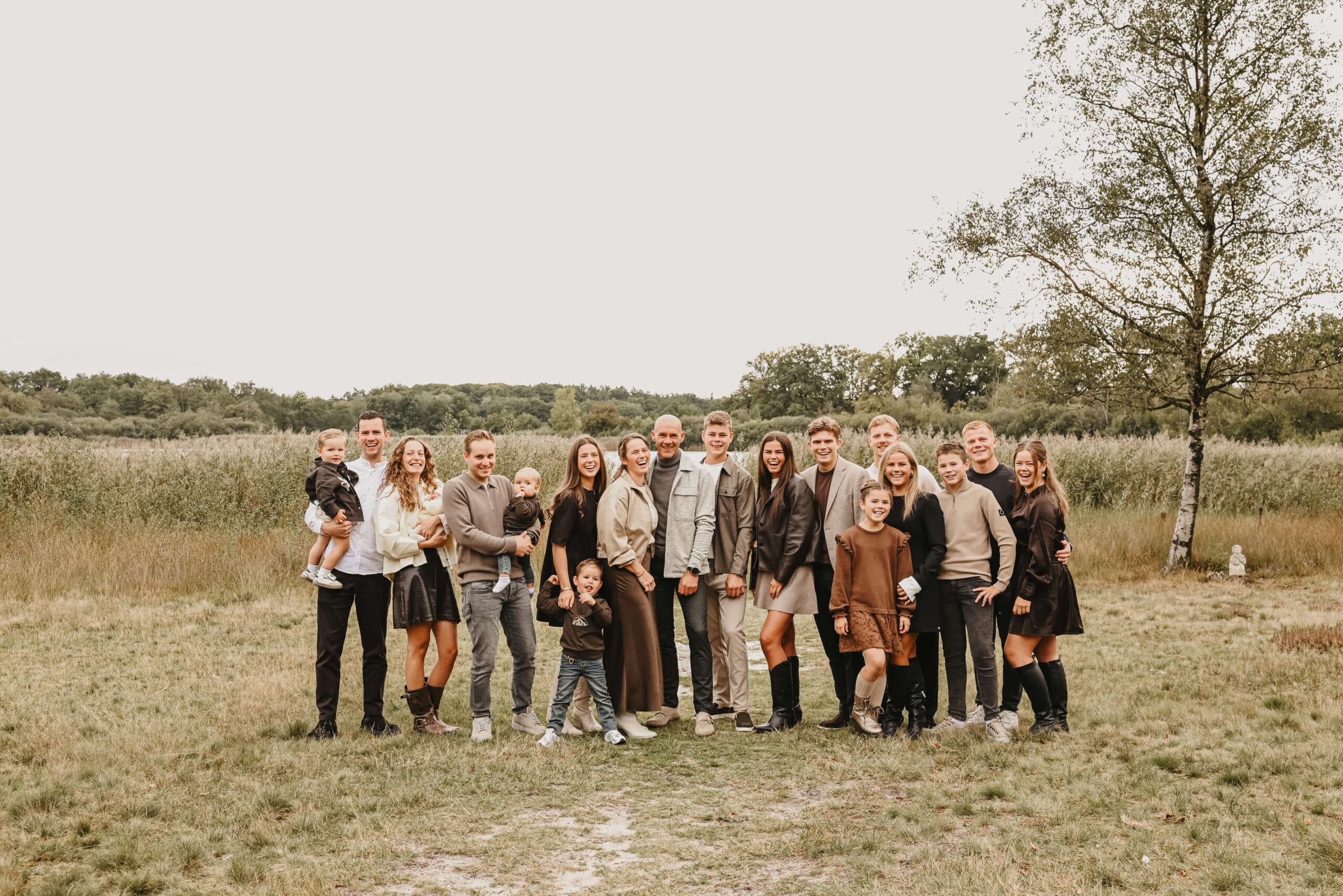 Grote familie samen op een rij in het veld – Studio Roos Fotografie