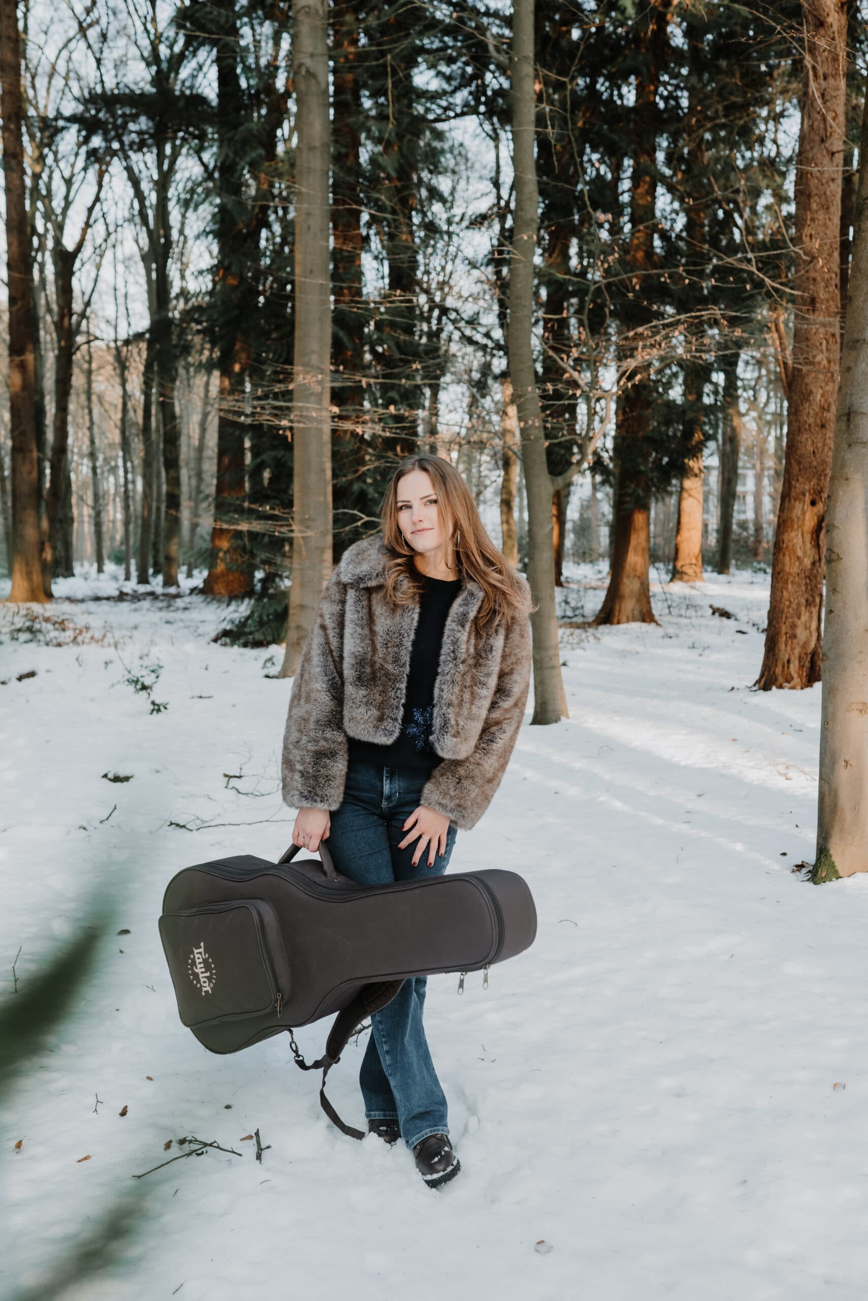 Muzikante met gitaarkoffer in besneeuwd bos – Studio Roos Fotografie