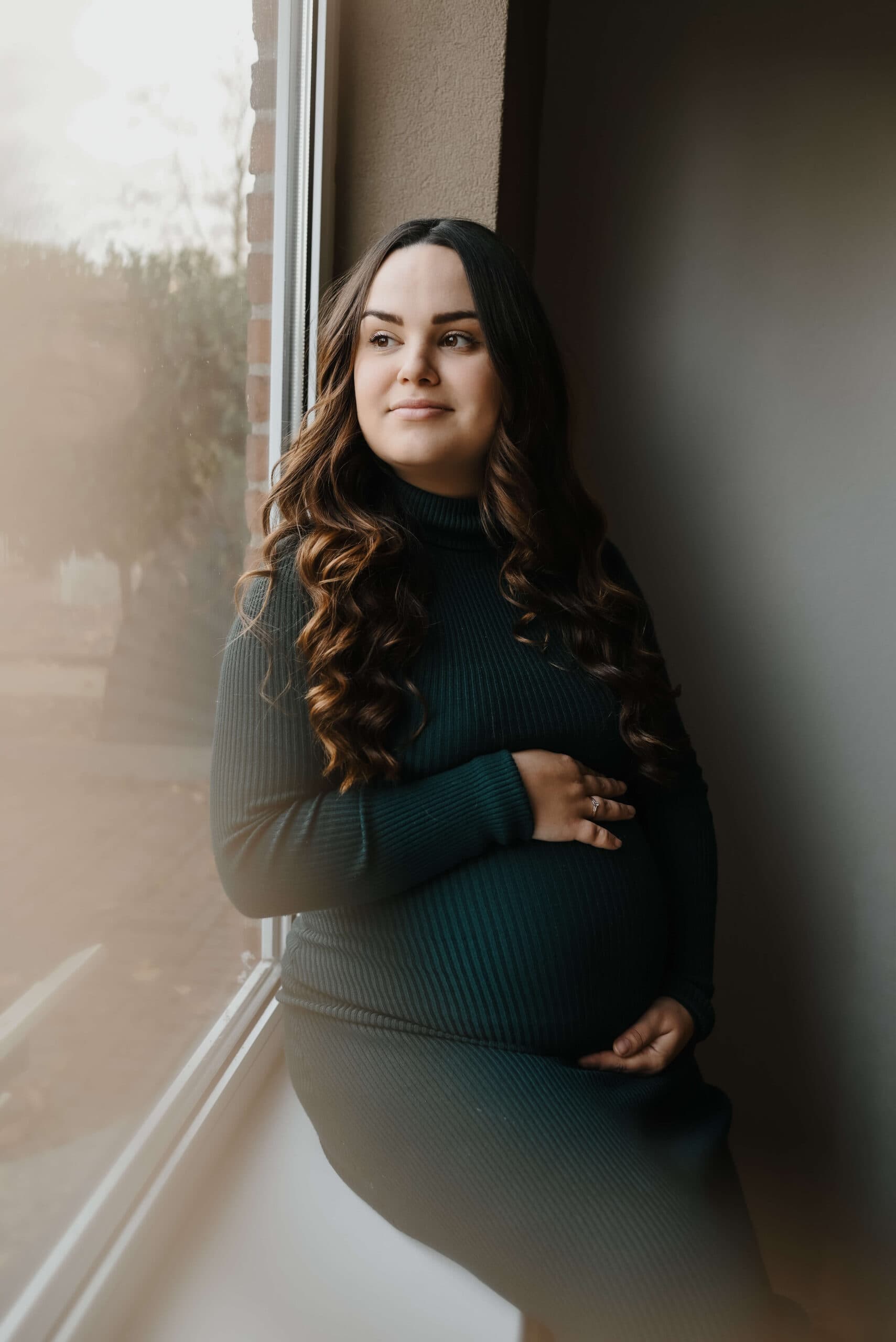 Zwangere vrouw kijkt uit het raam – Studio Roos Fotografie