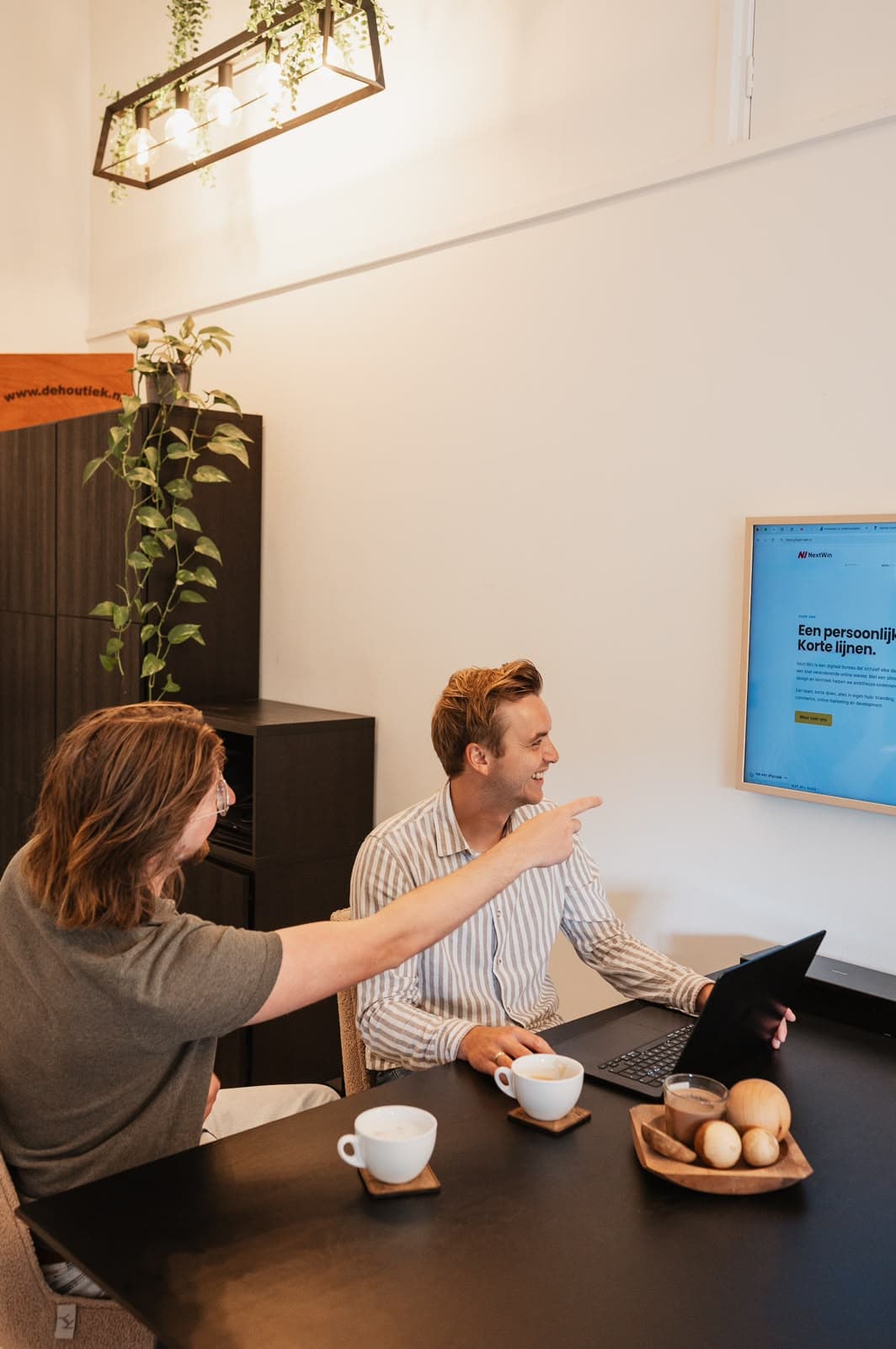 Overleg aan de vergadertafel, wijzend naar een ingelijst ontwerp – Studio Roos Fotografie