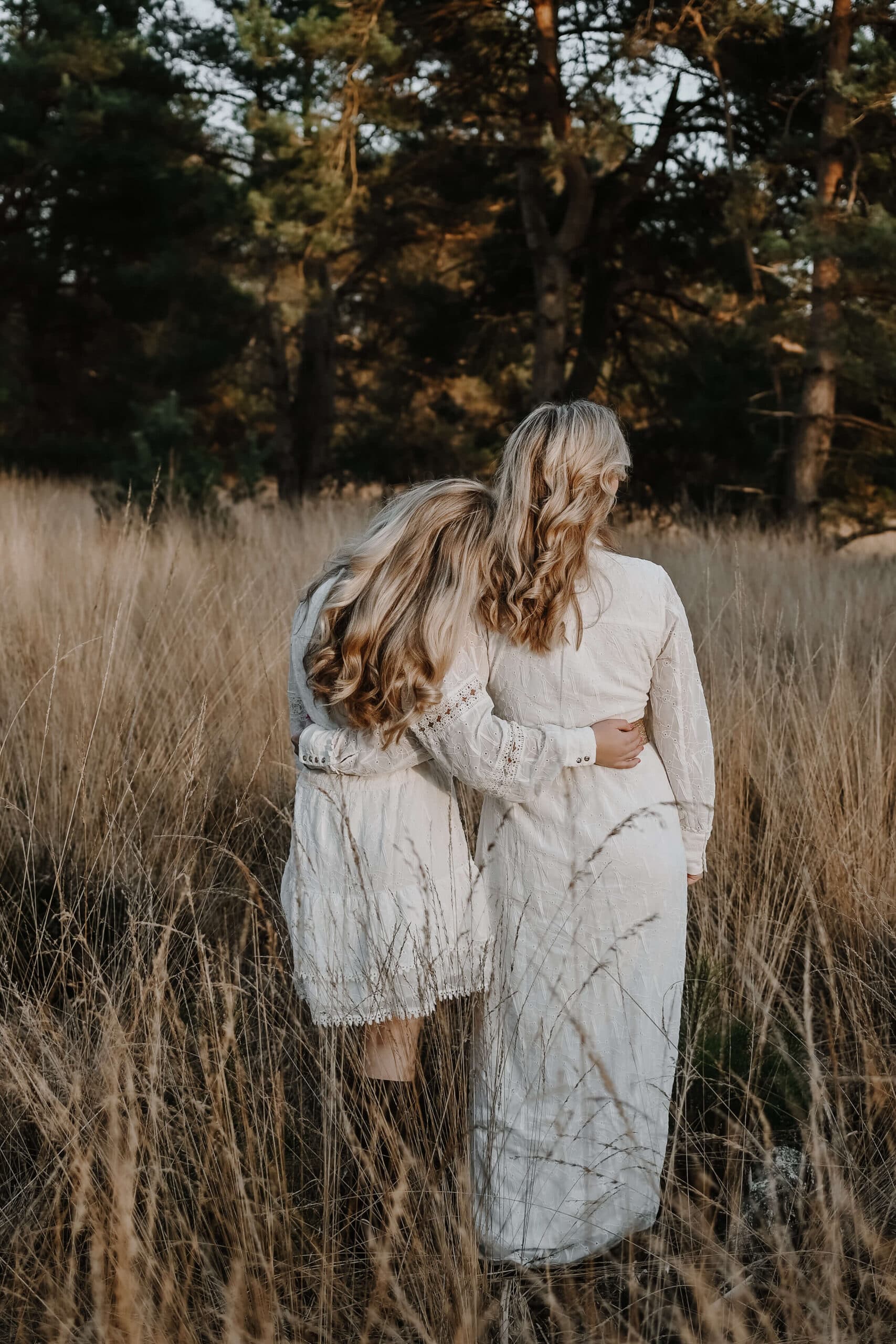 Moeder en dochter lopen gearmd door hoog gras – Studio Roos Fotografie